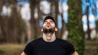 Man breathing in forest with head back and eyes closed